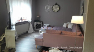Schicke EInrichtung, rosa-lila Sofa graue Wände, viel Weiß