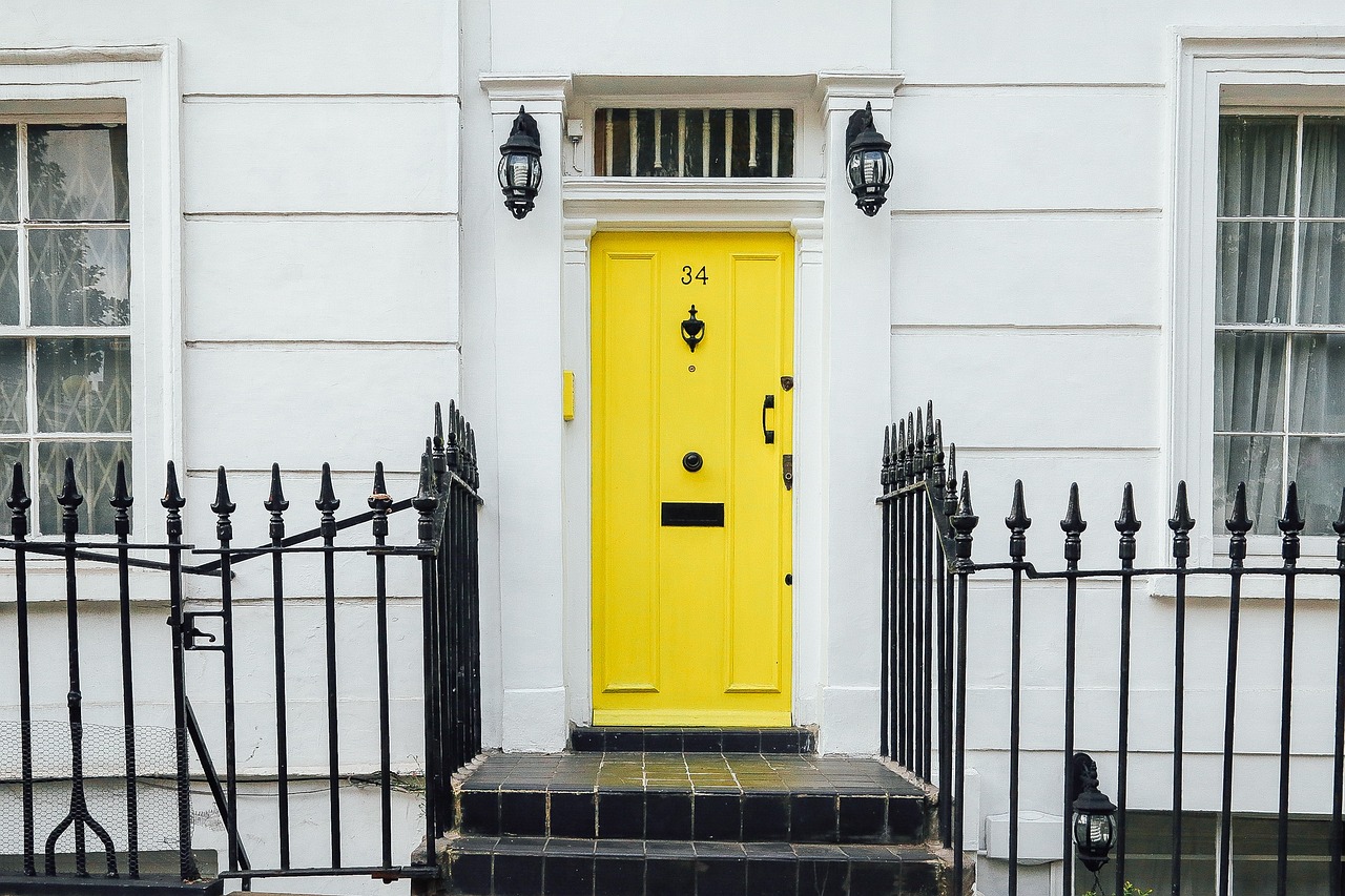 Kleiner Treppenzugang zu einem weißen Haus mit gelber Tür