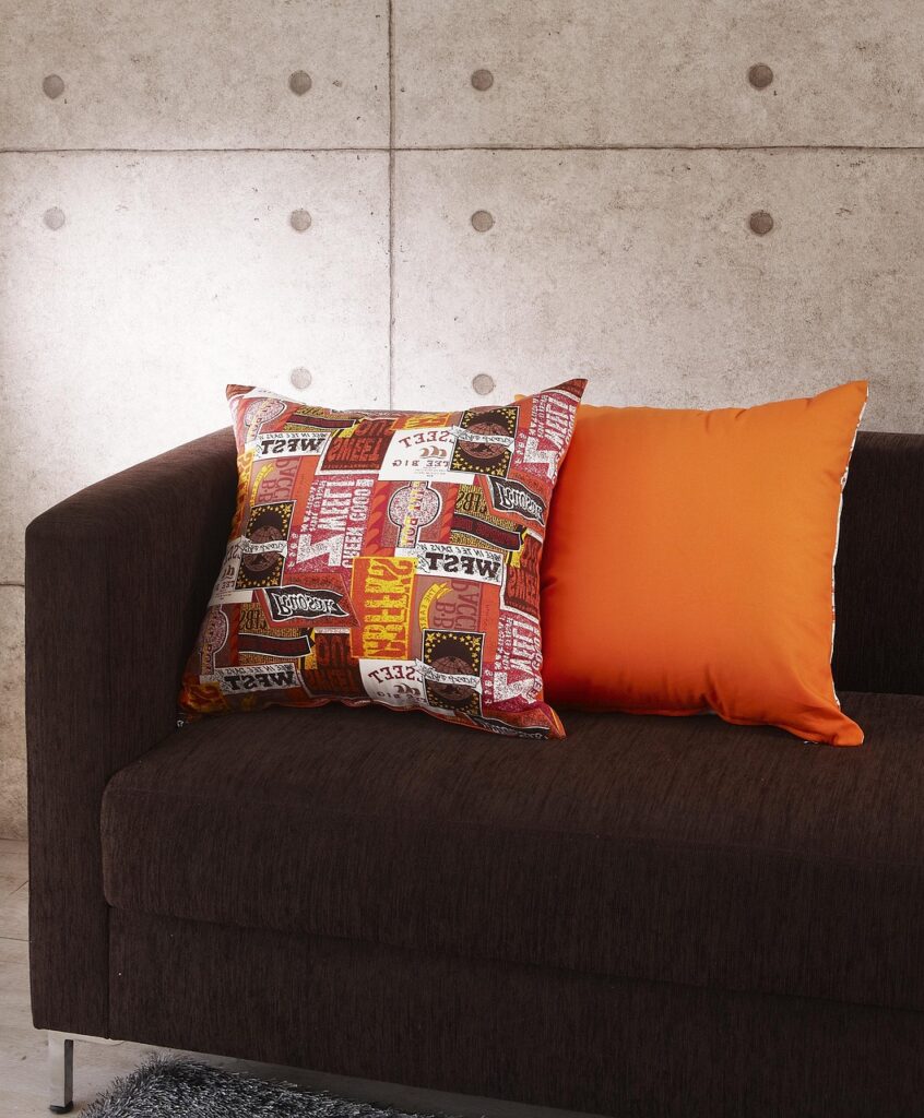 Elegante Kissen auf Sofa, eines bedruckt eines orange