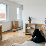 Frau sitzt in halbleerer Wohnung mit Umzugskartons